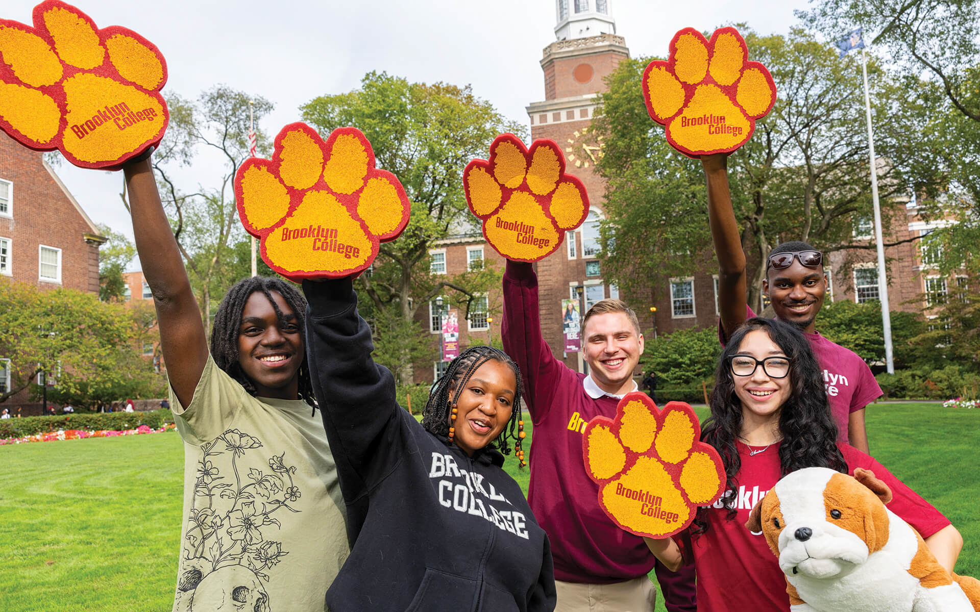 A group of students hold up bulldog paws on the East Quad