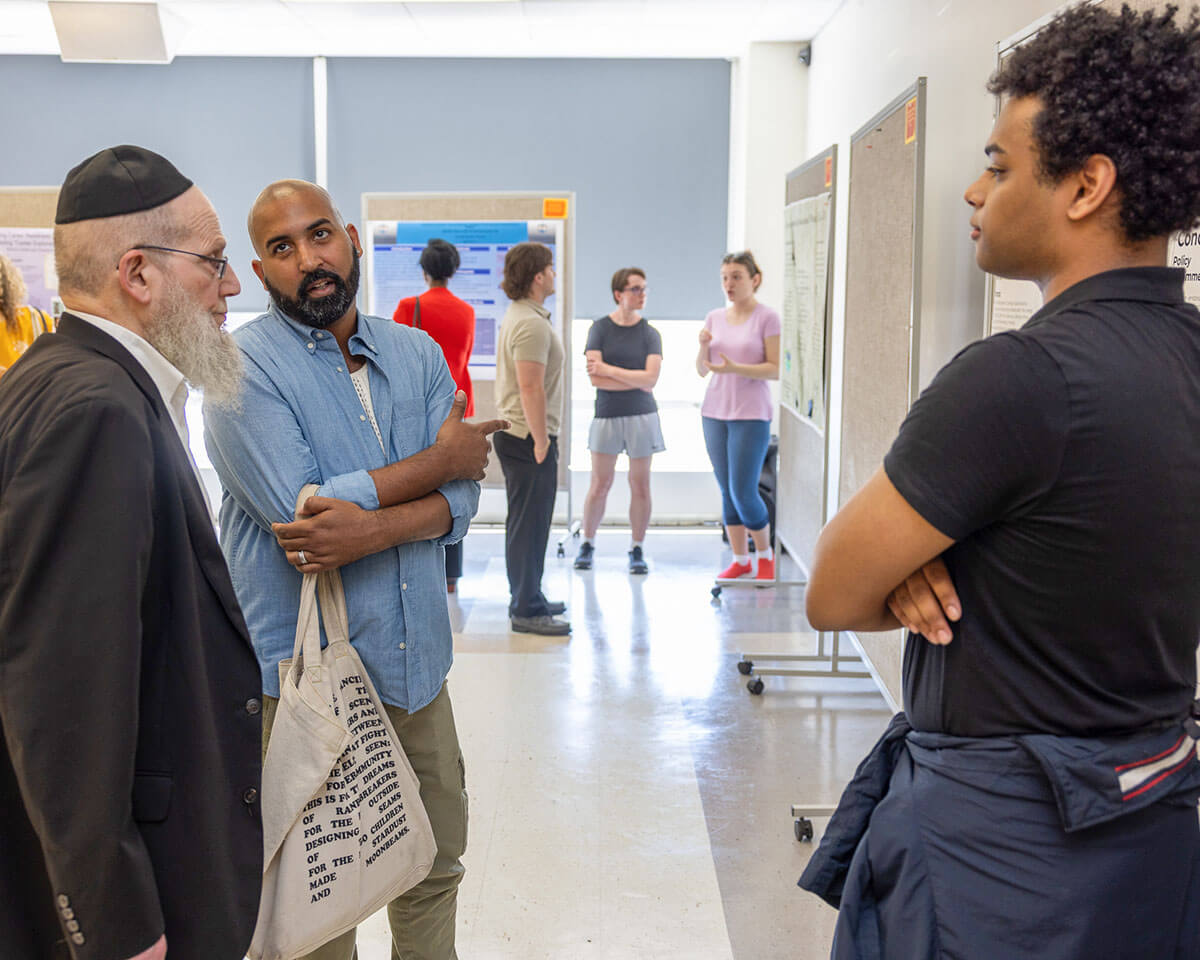 Yehuda Klein, Yehuda L. Klein, Professor of Economics; Stalin Haeger-Espinal, Sustainability Coordinator; speak with a student about his research project.