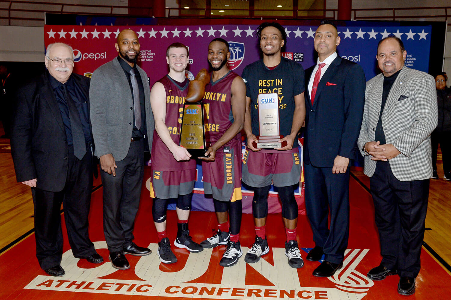 2020 CUNYAC Men's Basketball Championship trophy ceremony: (L–R) Bruce Filosa, director of athletics; Jeffrey Jean-Baptiste, head men's basketball coach; Michael Tesoriero, Jordan Wright, Noah Shy, Albert Barbosa, associate head men's basketball coach; Hector Batista, CUNY executive vice chancellor/chief operating officer